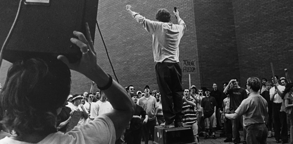 Shea Gunther giving a speech, standing on a trash can, at a RCC rally held on the campus of the Rochester Institute of Technology a few weeks into April, 1998.